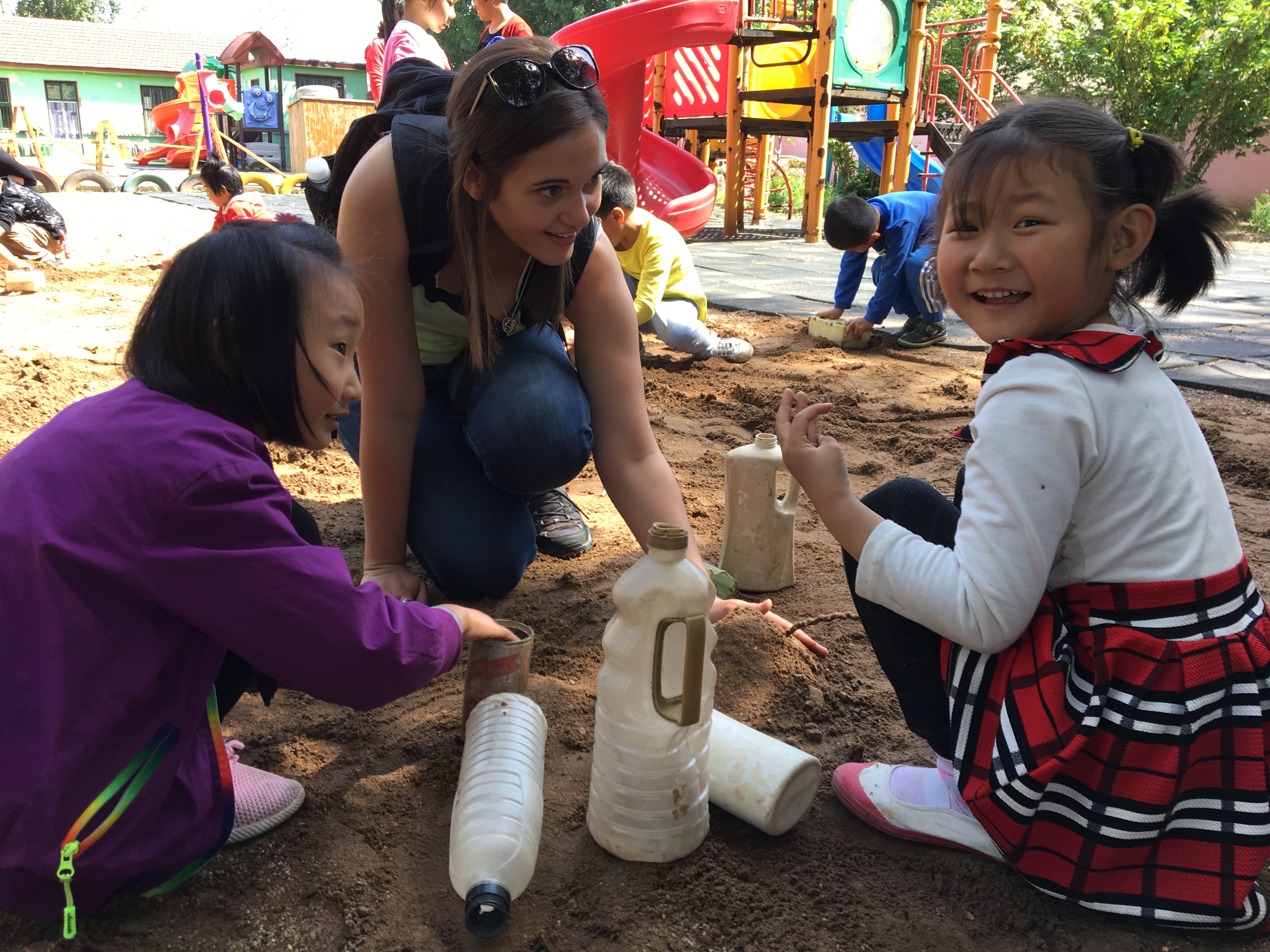 Chinese students playing in the sand with Saint Vincent student